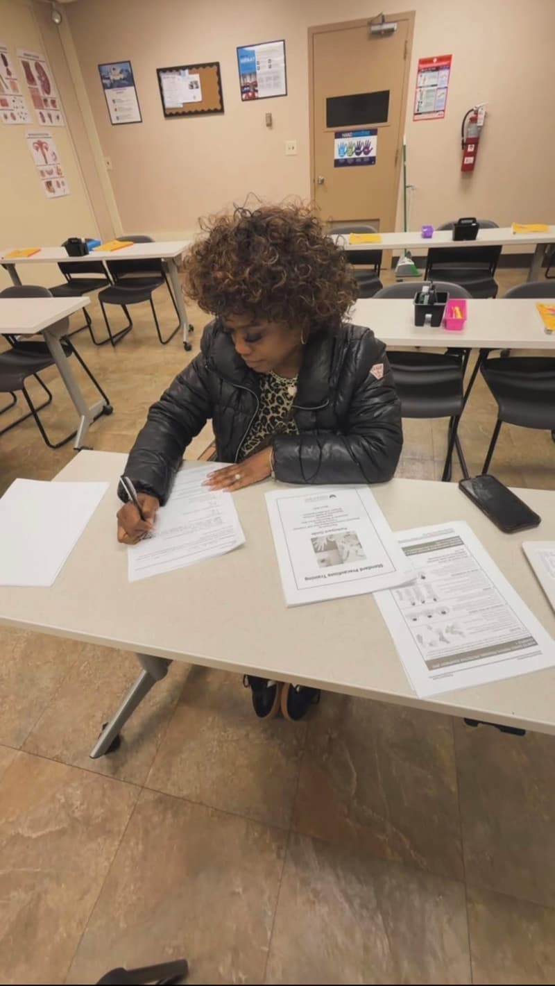 A student at Empower Ability working through Standard Precautions course materials at a classroom table.